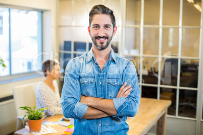 Smiling man standing arms crossed with his partner behind