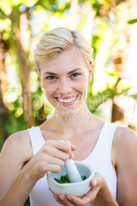 Happy blonde woman mixing herbs