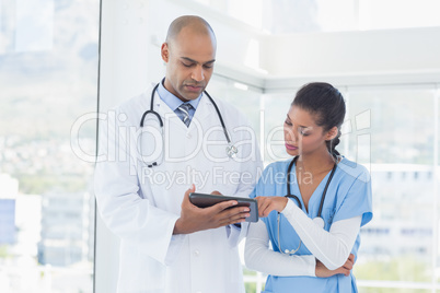 Smiling doctors working with tablet together