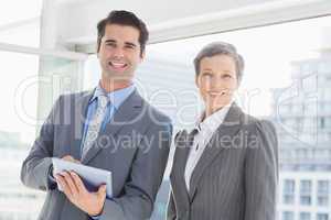 Business colleagues smiling at camera and holding tablet