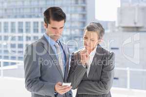 Business colleagues looking at mobile phone