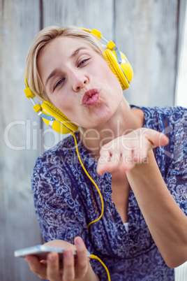 Pretty blonde woman listening music with her mobile phone and bl