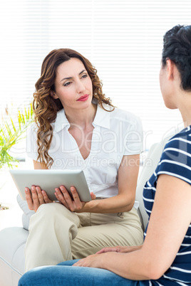 Therapist listening her patient and holding tablet