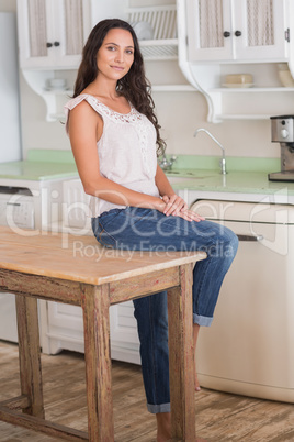 Pretty brunette sitting on table looking at camera
