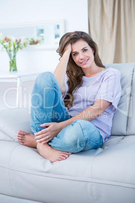 Happy brunette on couch smiling at camera