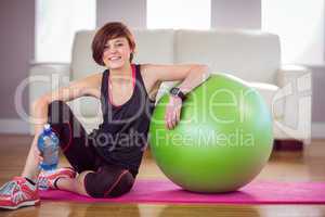 Fit woman sitting next to exercise ball