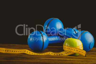 Blue dumbbells with green apple and measuring tape