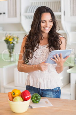 Pretty brunette using tablet pc and preparing salad