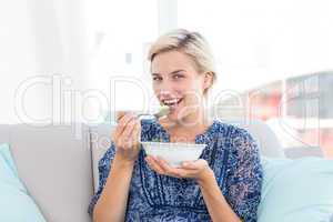 Pretty blonde woman eating bowl of salad
