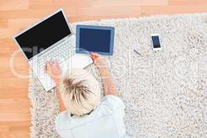 Pretty blonde woman lying on the floor while using her laptop an