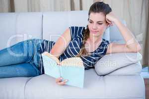 Concentrated woman reading a book on couch