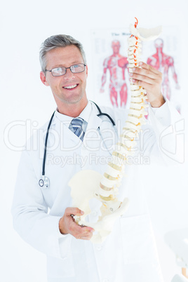 Doctor holding anatomical spine and smiling at camera