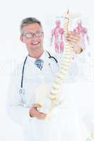 Doctor holding anatomical spine and smiling at camera