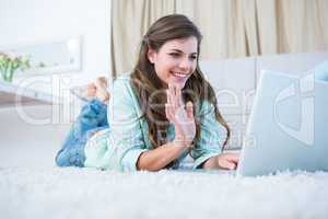 Happy woman using her tablet pc waving
