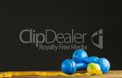 Blue dumbbells with green apple and measuring tape