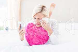 Blonde woman holding her mobile phone and crying