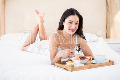 Pretty brunette eating her breakfast on bed