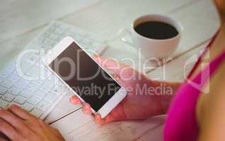 Woman using her smartphone and keyboard