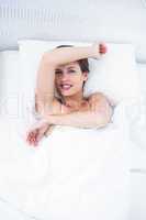 Happy woman in her bed smiling at camera