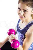 Fit woman lifting dumbbell sitting on ball