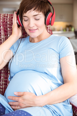 Pregnant woman putting headphones over bump