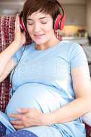 Pregnant woman putting headphones over bump