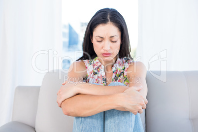 Pretty brunette feeling sad on couch