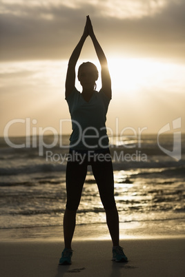 Sporty brunette stretching on the beach