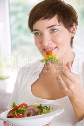 Pregnant woman having bowl of salad