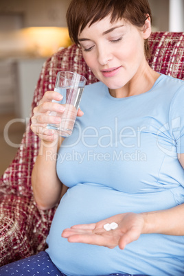 Pregnant woman taking a vitamin tablet