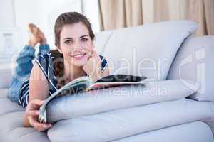 Happy woman reading a magazine on couch