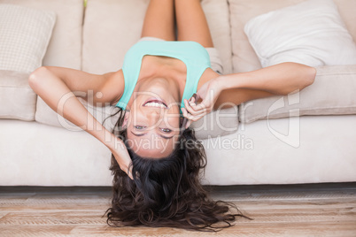 Pretty brunette lying upside down on couch