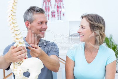 Physiotherapist showing spine model to his patient