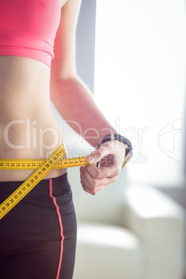 Slim woman measuring waist with tape measure