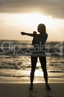 Sporty brunette stretching on the beach