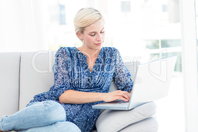 Pretty blonde woman using her laptop on the couch