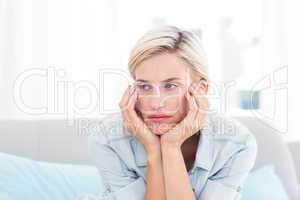 Thoughtful blonde woman sitting on the couch