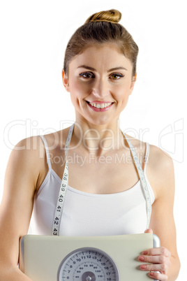 Slim woman holding scales and measuring tape