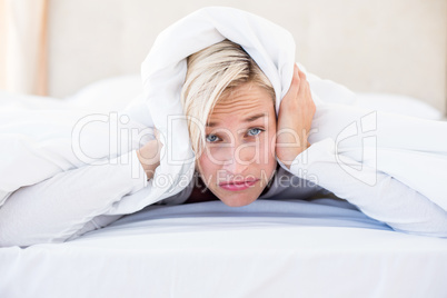 Upset blonde woman lying on the bed