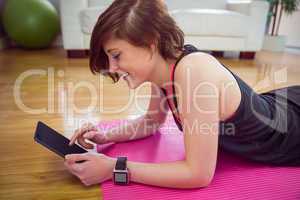 Fit woman using tablet pc on mat