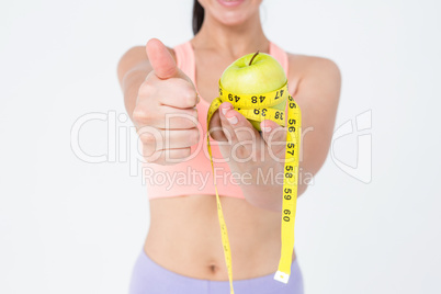 Slim woman holding apple with measuring tape