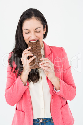 Smiling brunette biting bar of chocolate