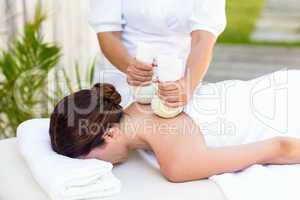 Brunette having massage with herbal compresses