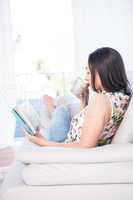 Pretty brunette reading a book on couch