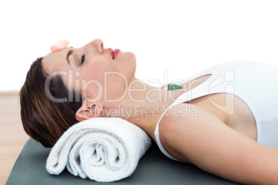 Relaxed brunette lying on mat with stones