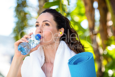 Fit beautiful brunette drinking water while listening music