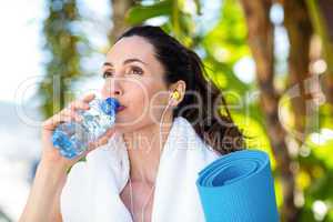 Fit beautiful brunette drinking water while listening music