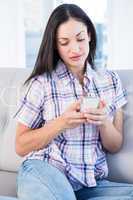 Pretty brunette using smartphone on couch