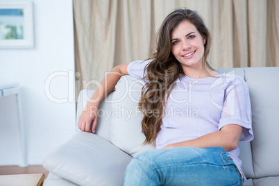 Happy brunette on couch smiling at camera