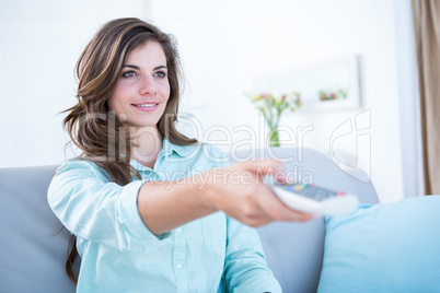 Happy brunette watching television on couch